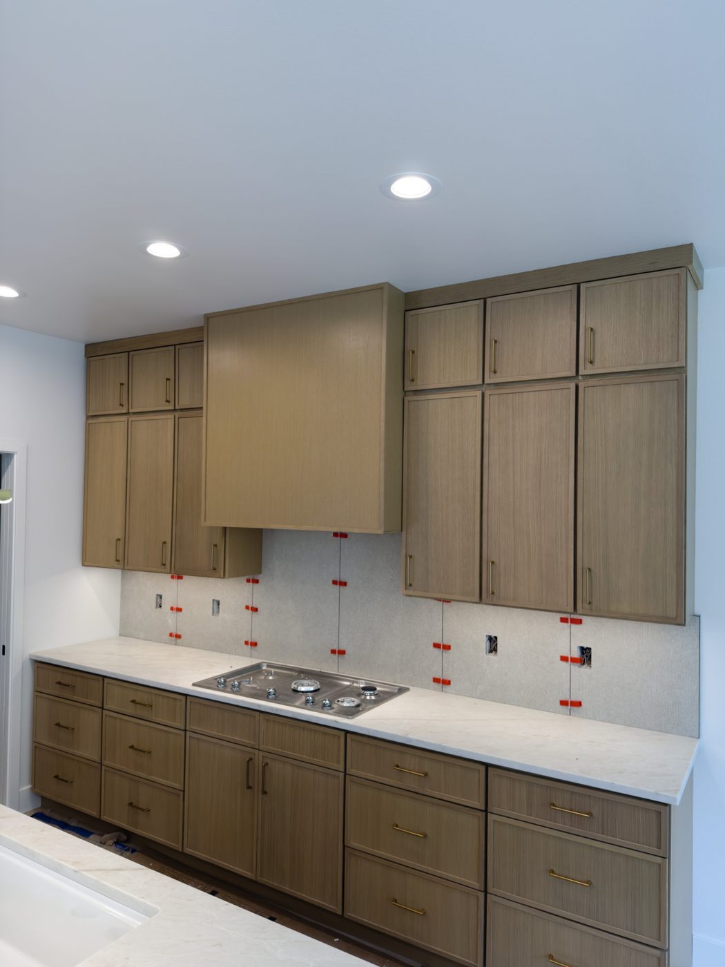 White oak base and wall cabinets around a gas cooktop