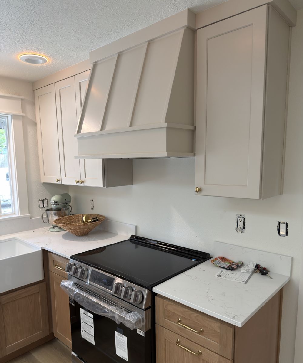 Greige uppers and range hood over white oak lowers